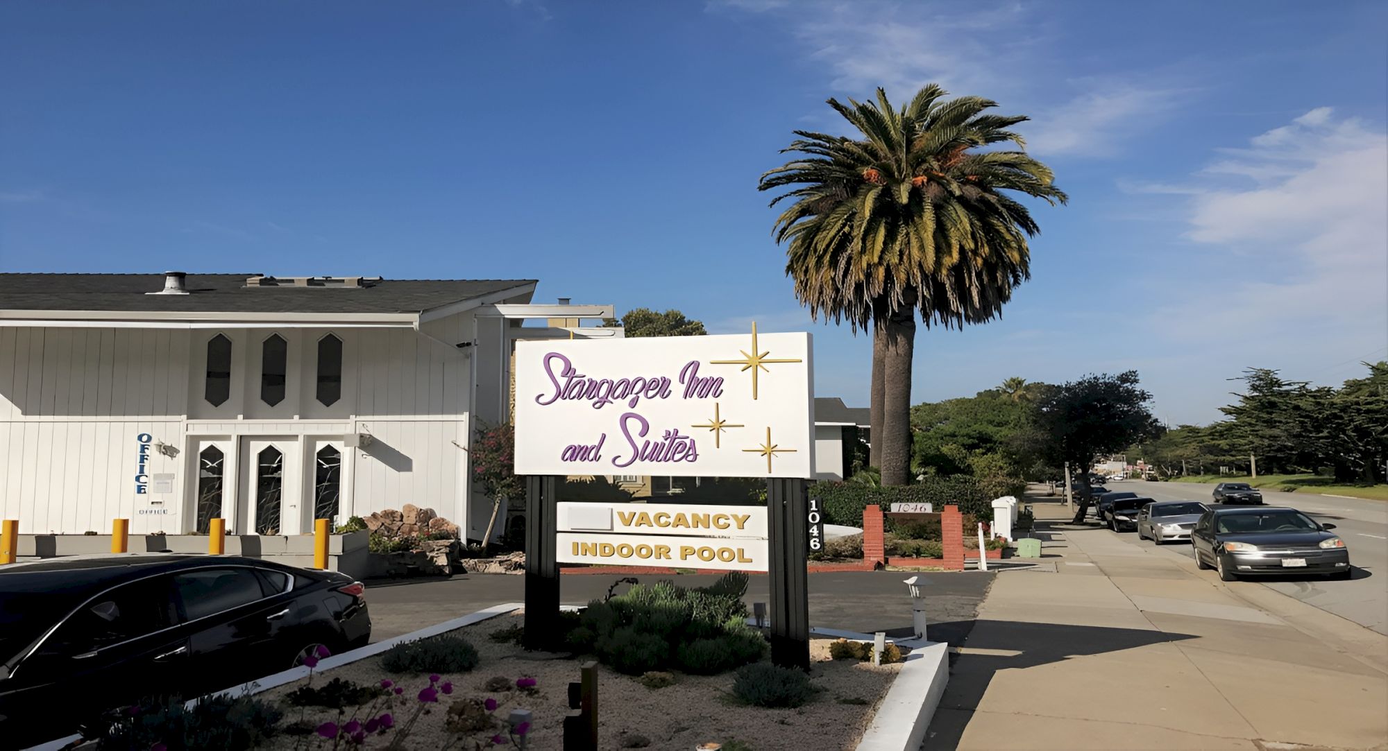 A motel with a large sign reading “Starrkings Inn and Suites” by a palm tree, a drive‑up lot, and a few cars along the street.