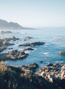 A rocky coastline with cliffs meeting a calm blue sea under a clear sky.